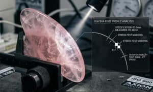 A rose quartz Gua Sha tool reveals distinct fracture lines under strong light.